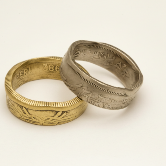 טבעות ממטבעות עתיקים מרחבי העולם בעבודת יד על רקע קרם של סטודיו צורפות פלוס