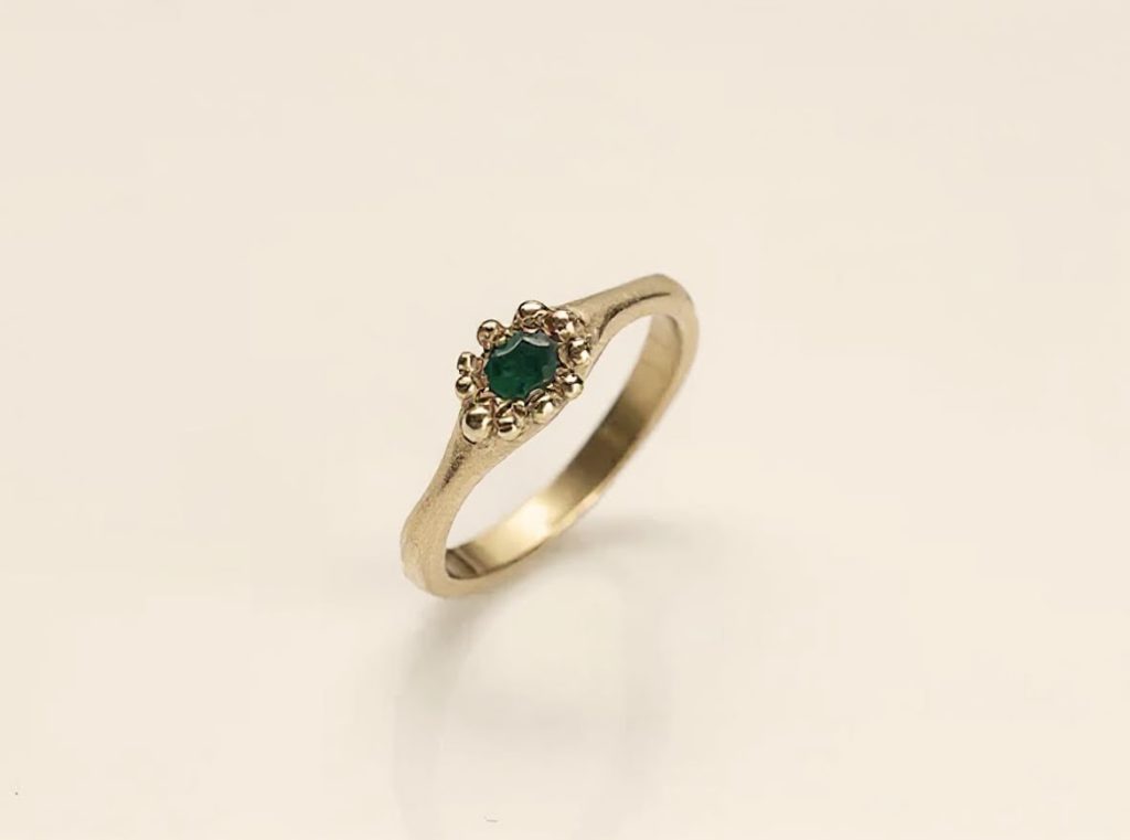 טבעת זהב 18 קראט בעבודת יד עם אבן אמרלד ירוקה מוקפת גושי זהב קטנים בעיצוב פרחוני
