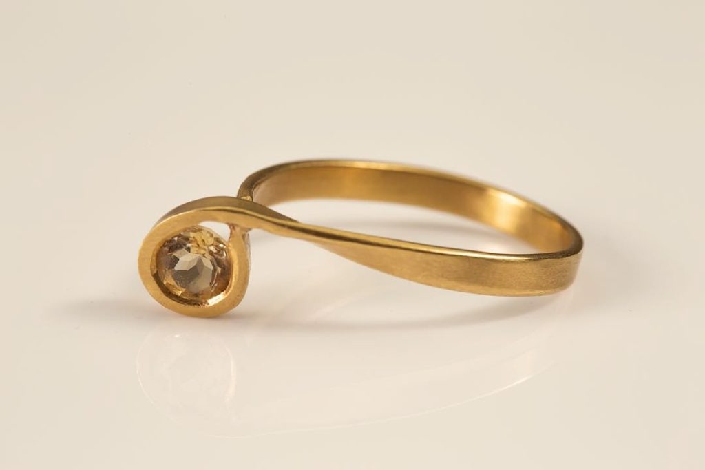 טבעת זהב 18 קראט עם עיצוב ספירלי משובצת באבן סיטרין עגולה, רקע לבן