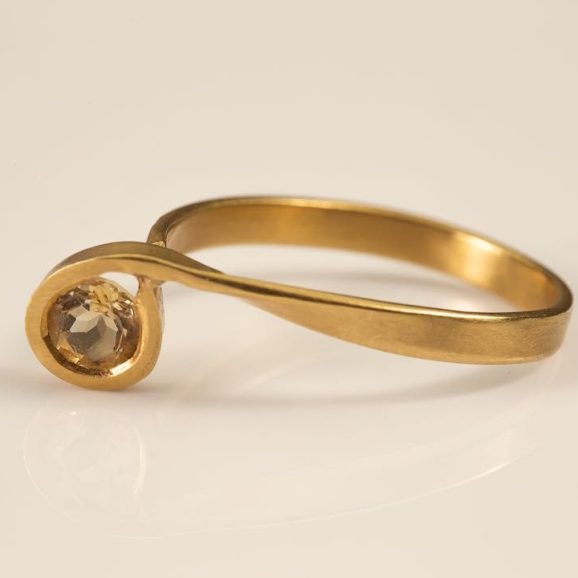 טבעת זהב 18 קראט עם עיצוב ספירלי משובצת באבן סיטרין עגולה, רקע לבן