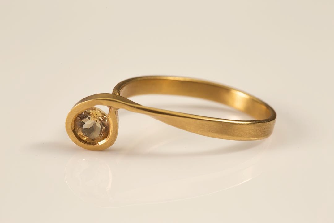 טבעת זהב 18 קראט עם עיצוב ספירלי משובצת באבן סיטרין עגולה, רקע לבן