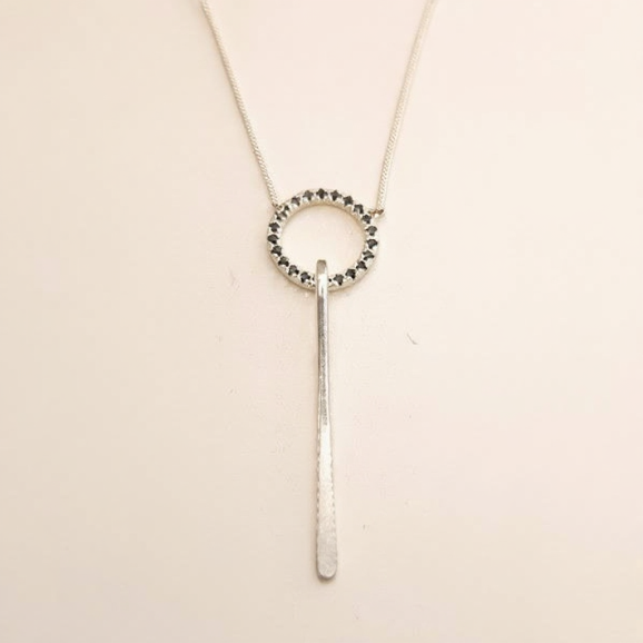 תליון זהב לבן בעבודת יד בעיצוב מעגל עם ספינלים שחורים ומוט מוארך