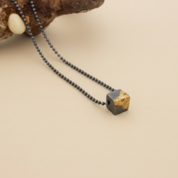 שרשרת כסף מושחר עם קוביית זהב טהור בעבודת יד על רקע קרם של סטודיו צורפות פלוס