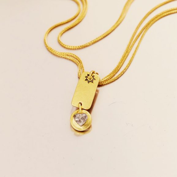 שרשרת זהב 18 קראט עם דיסקית מלבנית משובצת יהלומים שחורים ותליון לב יהלום גולמי.