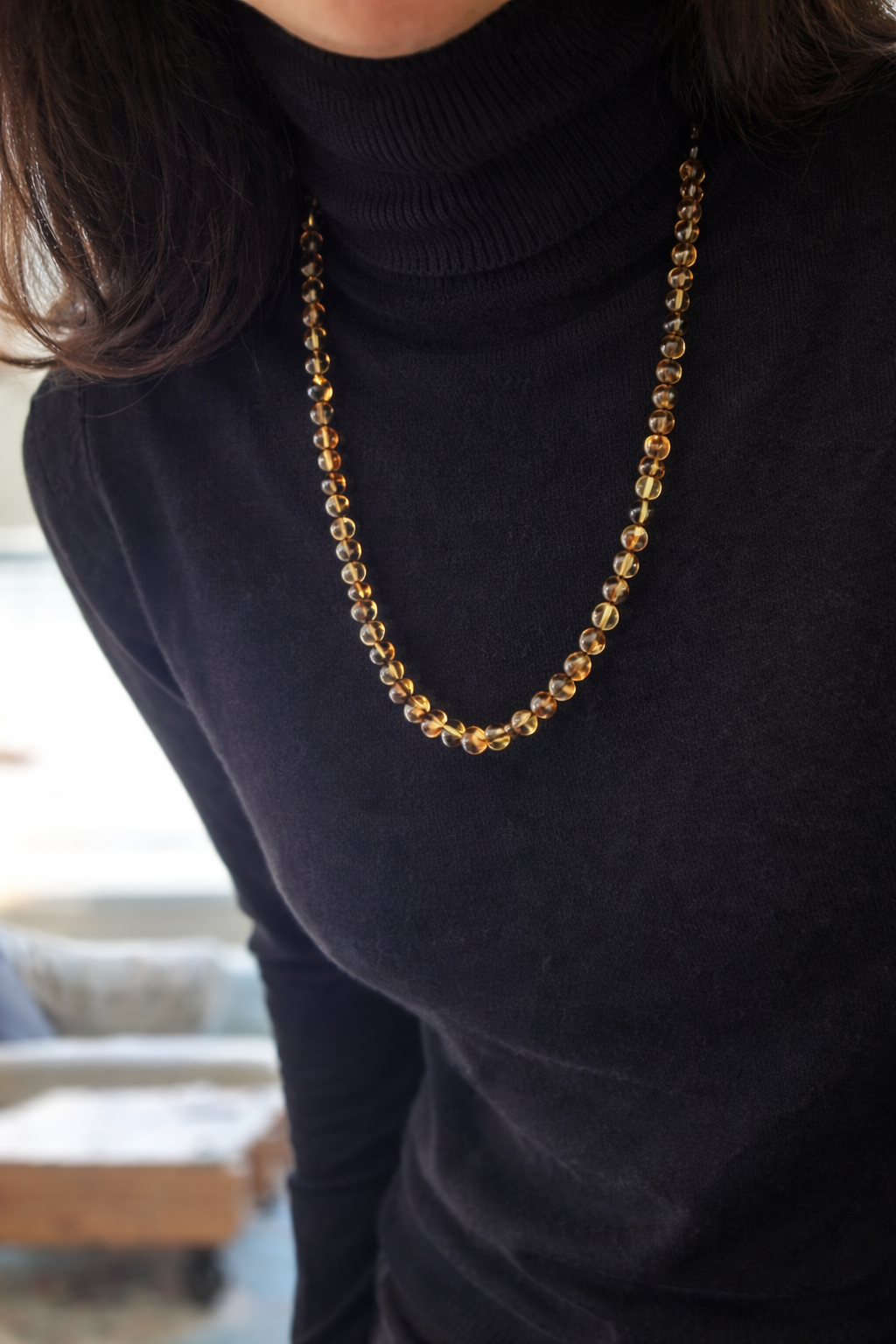 שרשרת ענברים קטנים בעיצוב עדין על גולף פשתן בהיר, תכשיט טבעי לנשים בעבודת יד